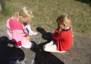 dziewczynki grają w kółko i krzyżyk kreda na chodniku